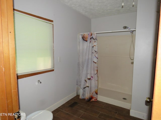 bathroom featuring curtained shower, visible vents, wood tiled floor, a textured ceiling, and baseboards