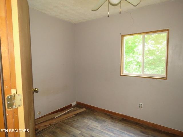 unfurnished room with ceiling fan, dark wood finished floors, and baseboards