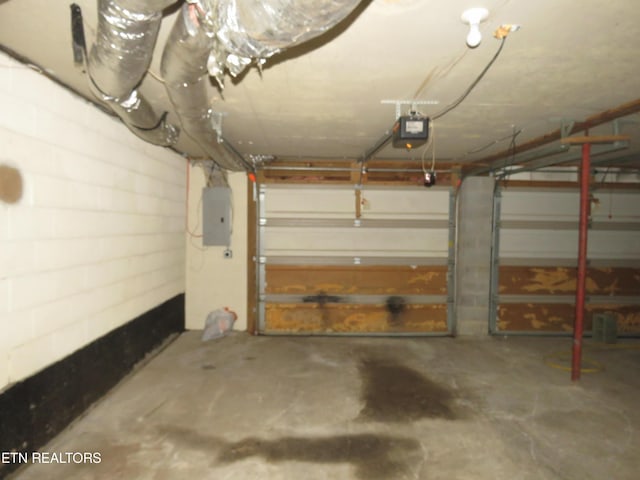 garage with concrete block wall, electric panel, and a garage door opener