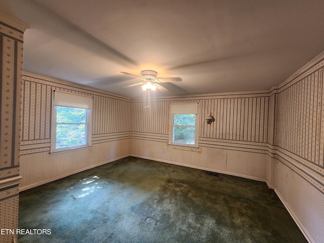 spare room with ceiling fan, a healthy amount of sunlight, and dark colored carpet