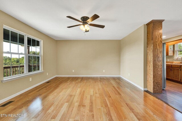 unfurnished room with light wood-type flooring, sink, and ceiling fan