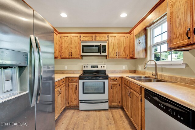 kitchen with stainless steel appliances, sink, and light hardwood / wood-style floors