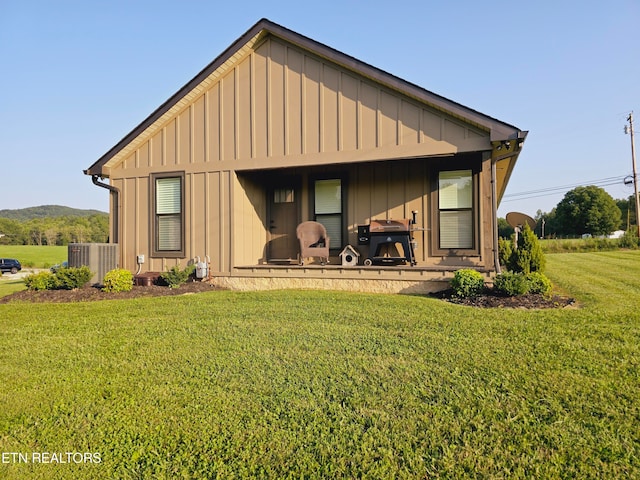 back of house with central AC unit and a yard