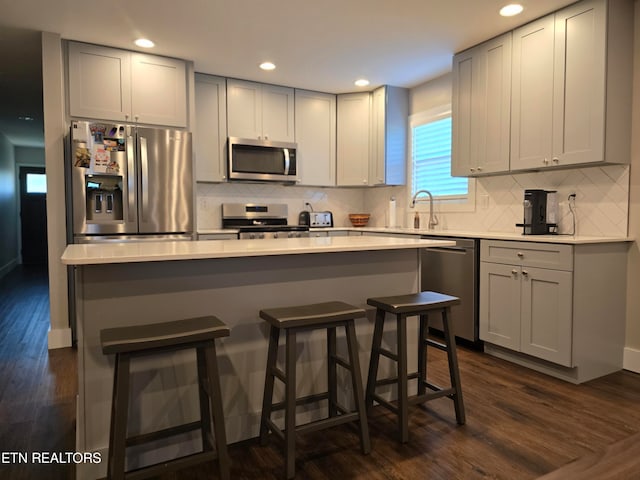 kitchen featuring a kitchen island, appliances with stainless steel finishes, dark hardwood / wood-style flooring, and gray cabinetry