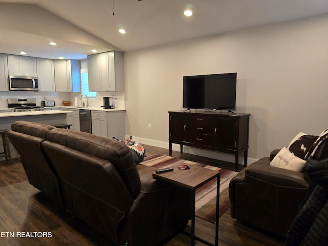 living room with dark hardwood / wood-style floors, vaulted ceiling, and sink