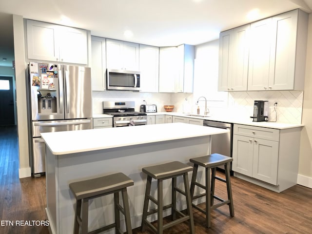 kitchen featuring a breakfast bar, dark wood-type flooring, tasteful backsplash, and stainless steel appliances