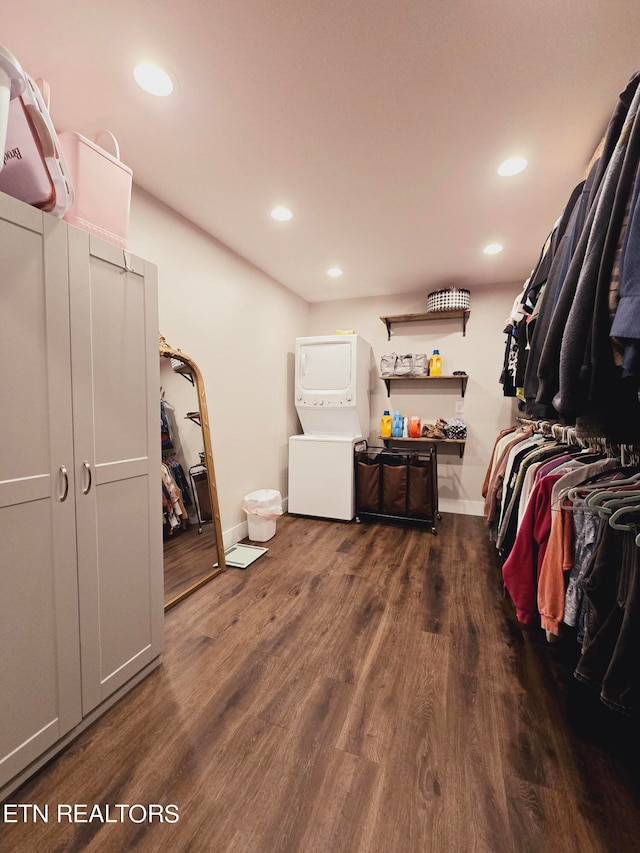 spacious closet with stacked washing maching and dryer and hardwood / wood-style floors