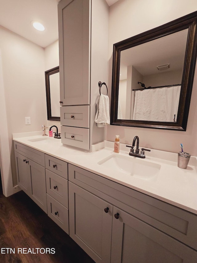 bathroom with hardwood / wood-style flooring and dual bowl vanity