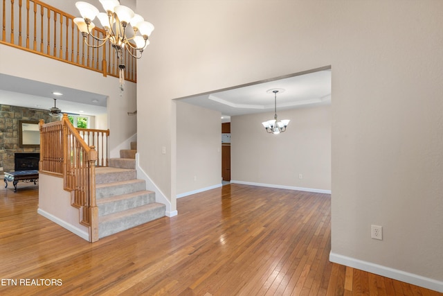 interior space with a notable chandelier, a fireplace, hardwood / wood-style flooring, and a raised ceiling