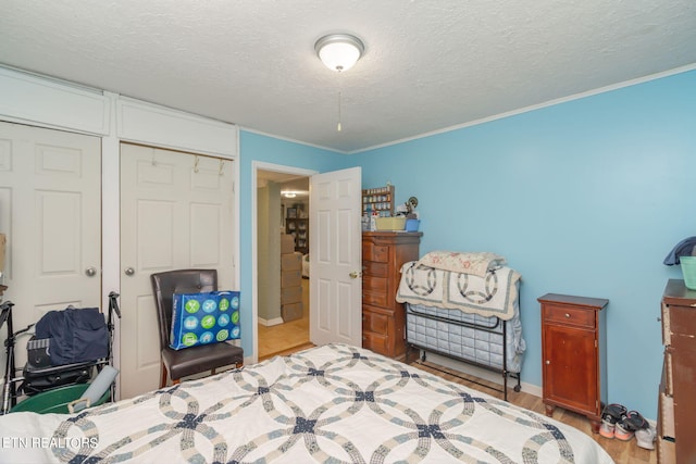 bedroom featuring a textured ceiling, a closet, light wood-style flooring, and crown molding