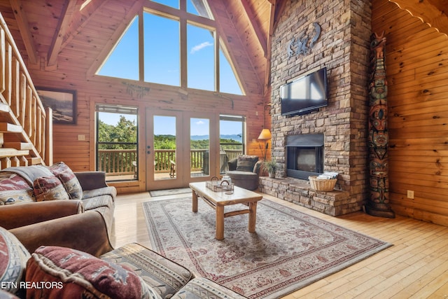 living room featuring a stone fireplace, light hardwood / wood-style floors, and wood walls