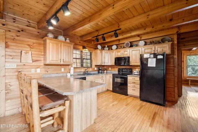 kitchen featuring light wood-type flooring, a wealth of natural light, beam ceiling, and black appliances