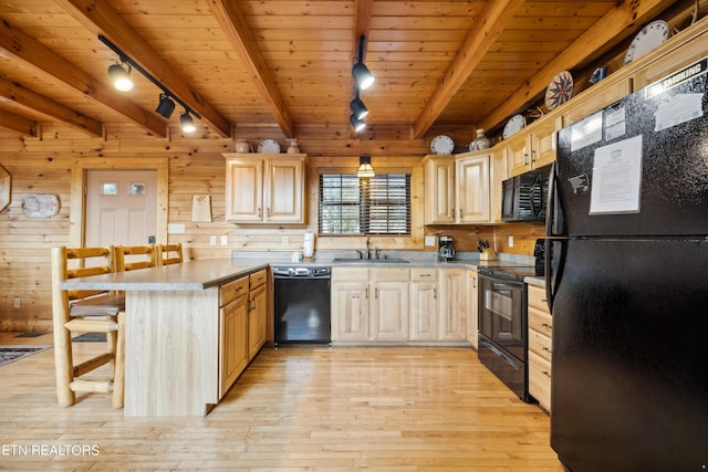 kitchen featuring pendant lighting, black appliances, light brown cabinets, a kitchen bar, and wood walls