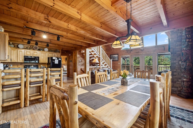 dining room with rail lighting, beam ceiling, wooden walls, wooden ceiling, and light wood-type flooring