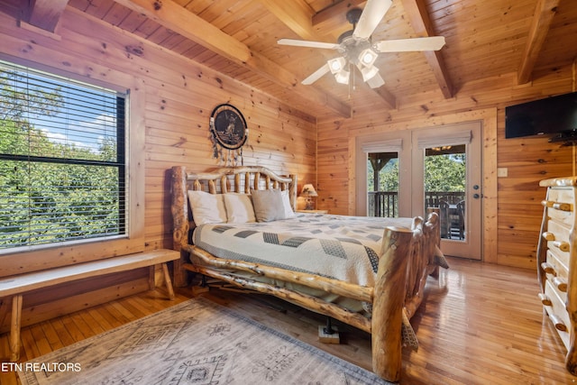 bedroom with multiple windows, wooden walls, and beam ceiling