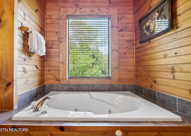 bathroom featuring a relaxing tiled tub and wooden walls