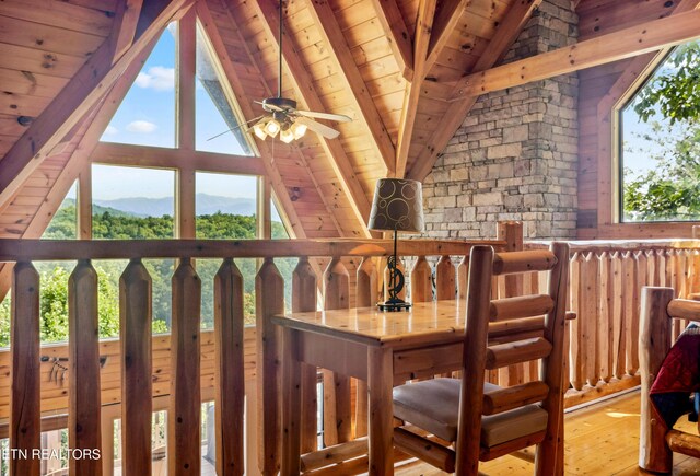 dining room with ceiling fan, hardwood / wood-style floors, wood ceiling, vaulted ceiling with beams, and a mountain view