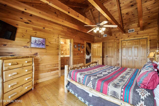 bedroom featuring wood walls, ceiling fan, wood-type flooring, a closet, and lofted ceiling with beams