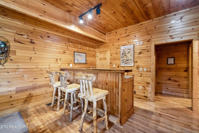 bar with wooden walls, light hardwood / wood-style flooring, and wood ceiling