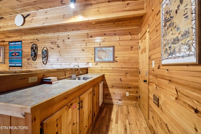 bar with sink, light wood-type flooring, and wood walls