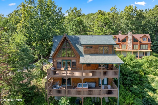 back of property featuring a wooden deck, a hot tub, and a patio