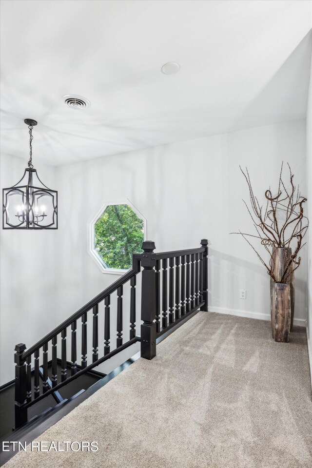 hall featuring carpet flooring and a chandelier