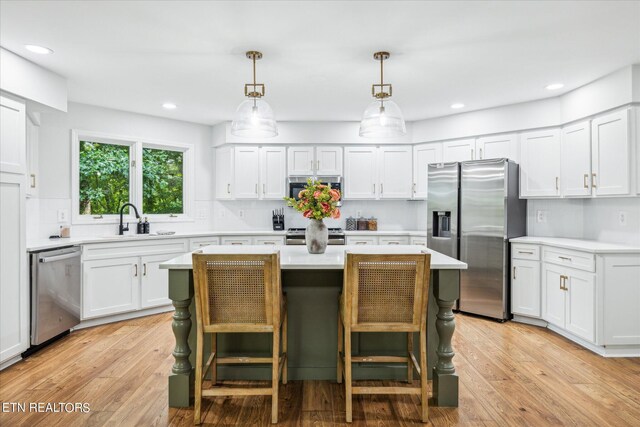 kitchen featuring a kitchen bar, stainless steel appliances, a center island, and light hardwood / wood-style floors