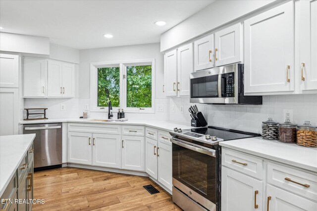 kitchen featuring white cabinets, stainless steel appliances, light hardwood / wood-style flooring, and decorative backsplash