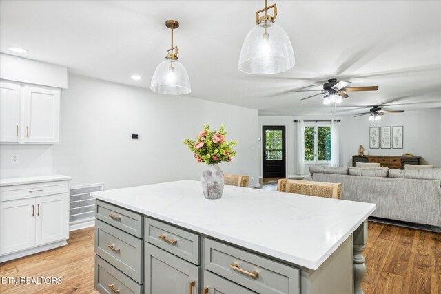 kitchen with a center island, light wood-type flooring, hanging light fixtures, and ceiling fan