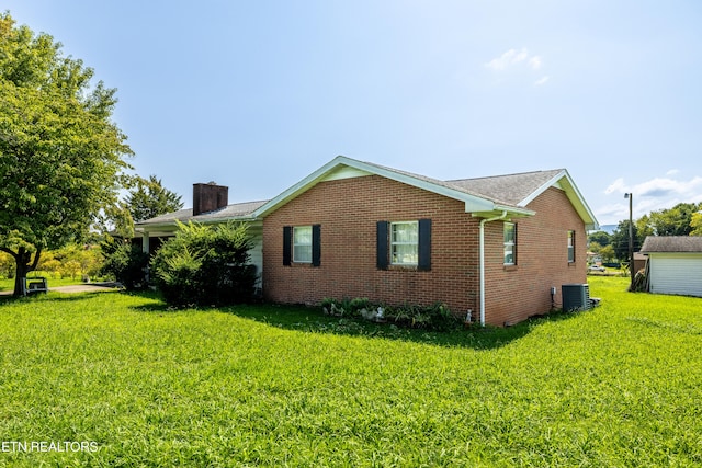 view of side of property featuring central air condition unit and a yard