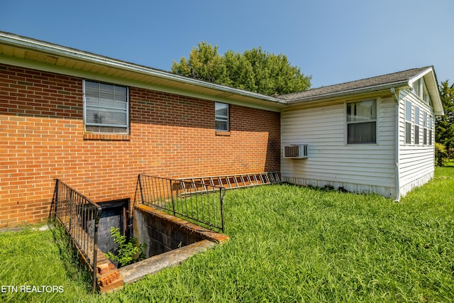 view of side of home with a wall unit AC and a yard