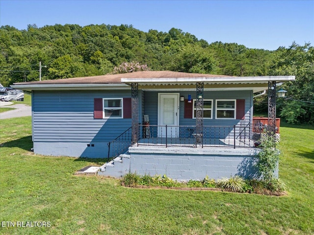 view of front facade featuring a porch, crawl space, a view of trees, and a front lawn