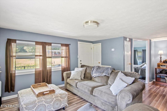 living room featuring a textured ceiling, baseboards, and wood finished floors