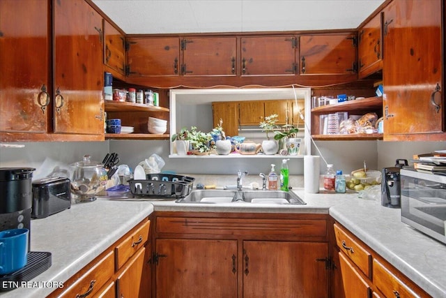 kitchen featuring open shelves, brown cabinetry, light countertops, and a sink