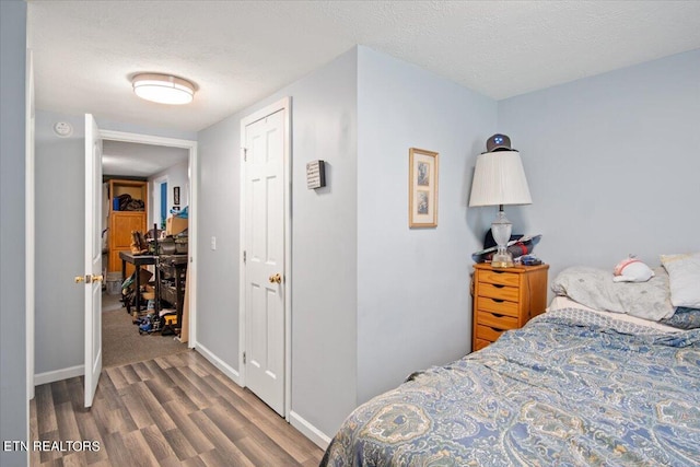 bedroom featuring dark wood-type flooring, a textured ceiling, and baseboards