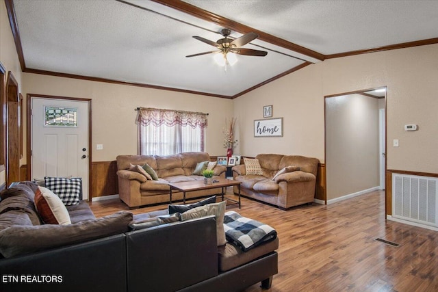 living room with lofted ceiling with beams, a textured ceiling, wood finished floors, visible vents, and ornamental molding