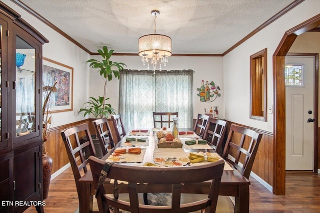 dining area featuring dark wood-style floors, crown molding, a chandelier, and a textured ceiling