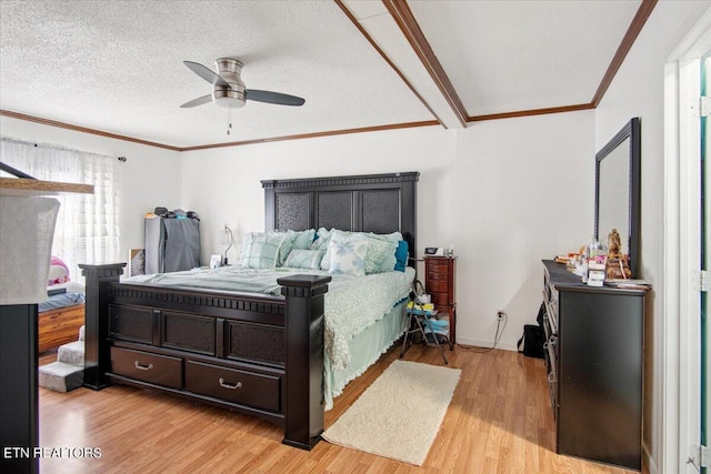 bedroom featuring ornamental molding, light wood-style flooring, a textured ceiling, and a ceiling fan