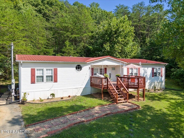 manufactured / mobile home with metal roof, stairway, a front lawn, and a wooden deck