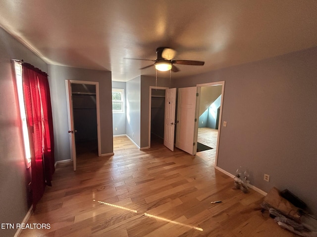 unfurnished bedroom with a walk in closet, a closet, hardwood / wood-style floors, and ceiling fan