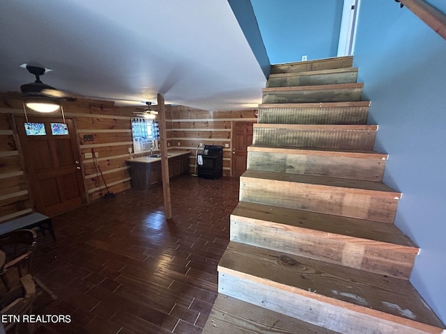 stairs with wooden walls, ceiling fan, and hardwood / wood-style flooring