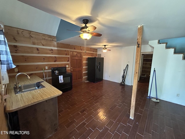 kitchen with ceiling fan, sink, wood walls, and black appliances