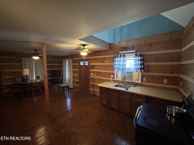 kitchen featuring ceiling fan, sink, stove, and wooden walls