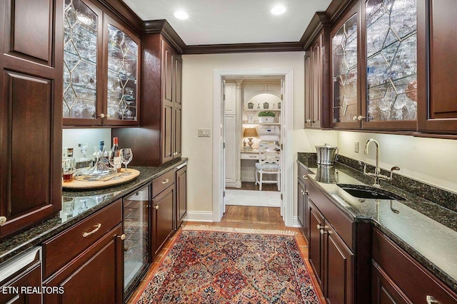 kitchen featuring sink, light hardwood / wood-style flooring, a wealth of natural light, and dark stone counters