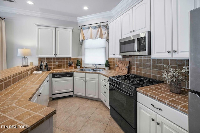 kitchen with appliances with stainless steel finishes, tasteful backsplash, tile counters, and white cabinets