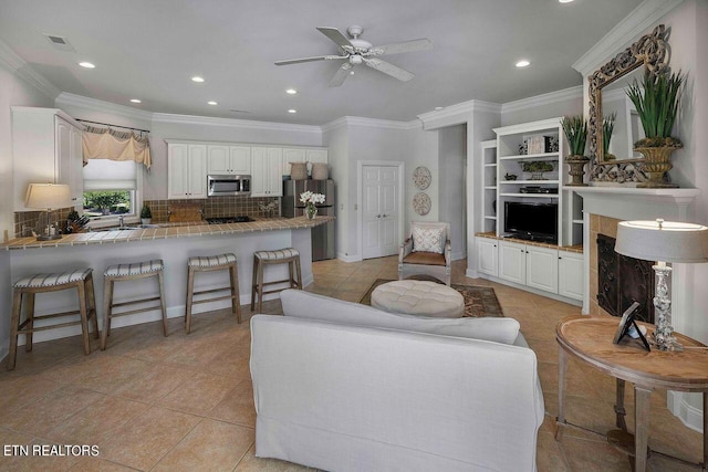 tiled living room with ceiling fan and crown molding