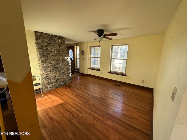 unfurnished living room with ceiling fan and dark wood-type flooring