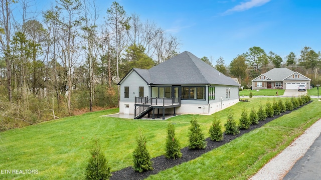 back of property with a sunroom, a wooden deck, roof with shingles, stairway, and a yard