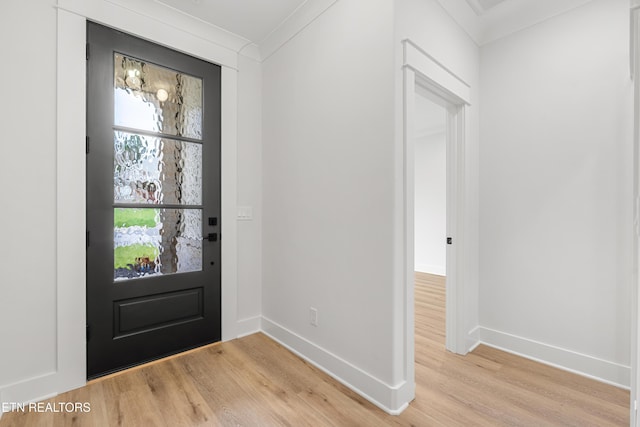 entryway with light wood-type flooring, baseboards, and ornamental molding