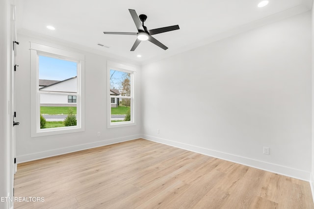 spare room featuring light wood finished floors, baseboards, a wealth of natural light, and visible vents